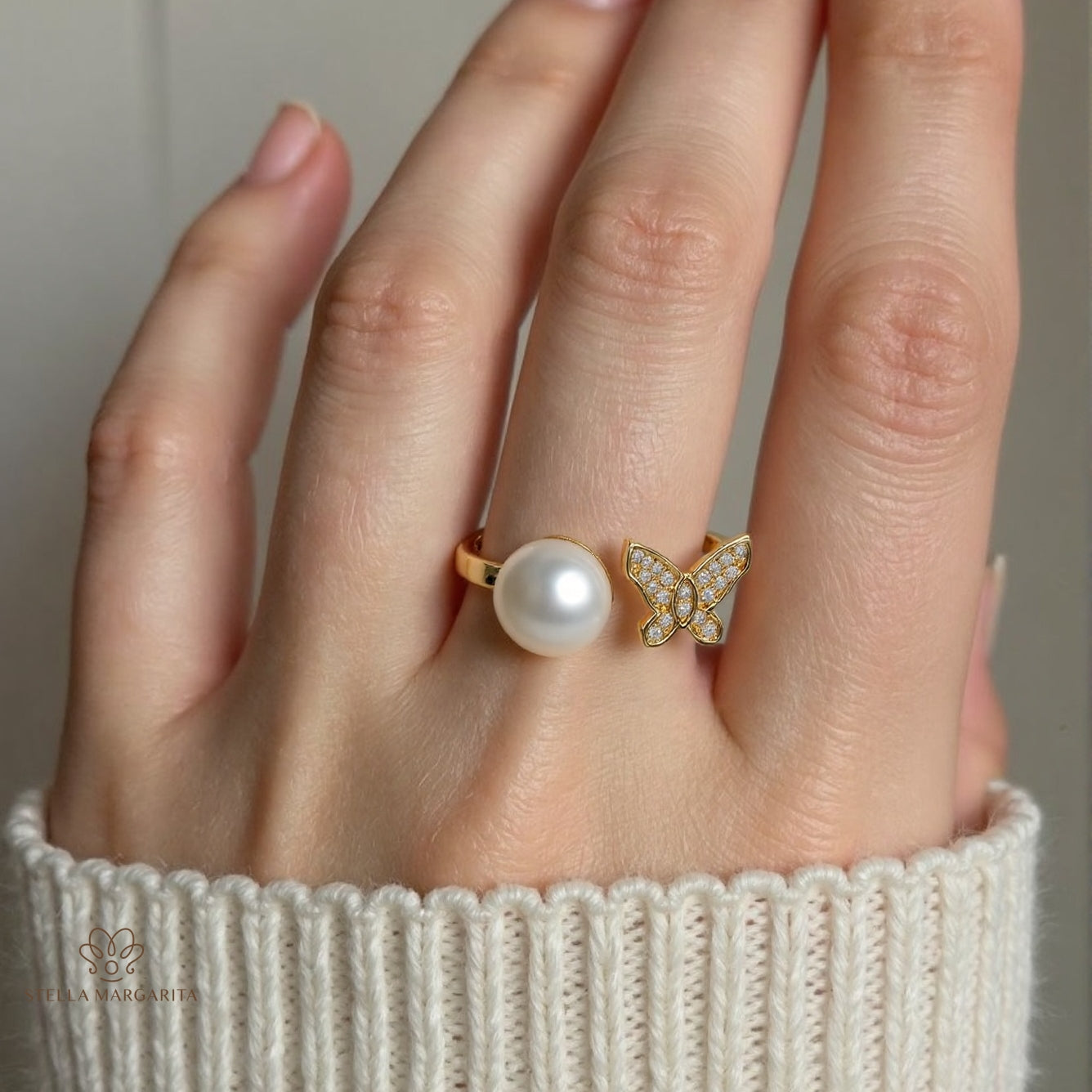 14K gold pearl butterfly ring with pearl and butterfly design worn on hand with cream knit sleeve