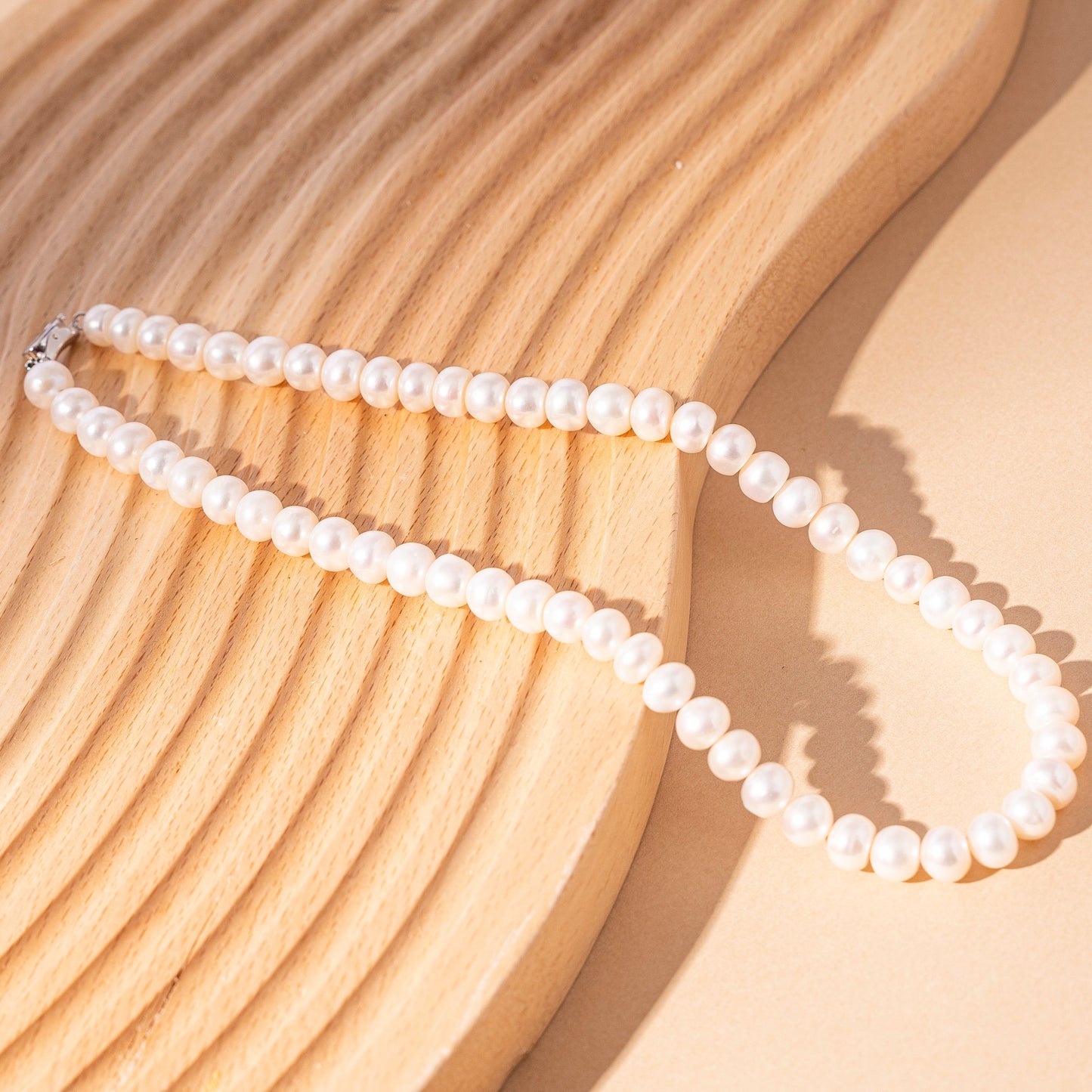 STELLA MARGARITA handcrafted pearl necklace for women displayed on a textured wooden surface