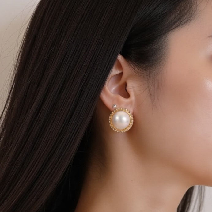 STELLA MARGARITA mabe pearl diamond rim earrings worn on woman’s ear with dark hair