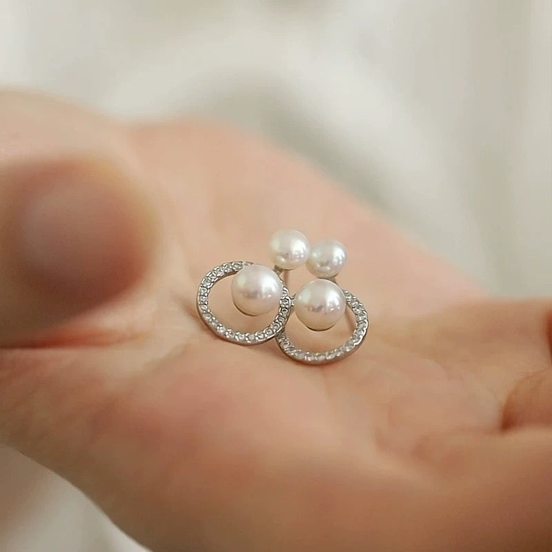 STELLA MARGARITA double freshwater pearl earrings with silver oval detailing held in hand