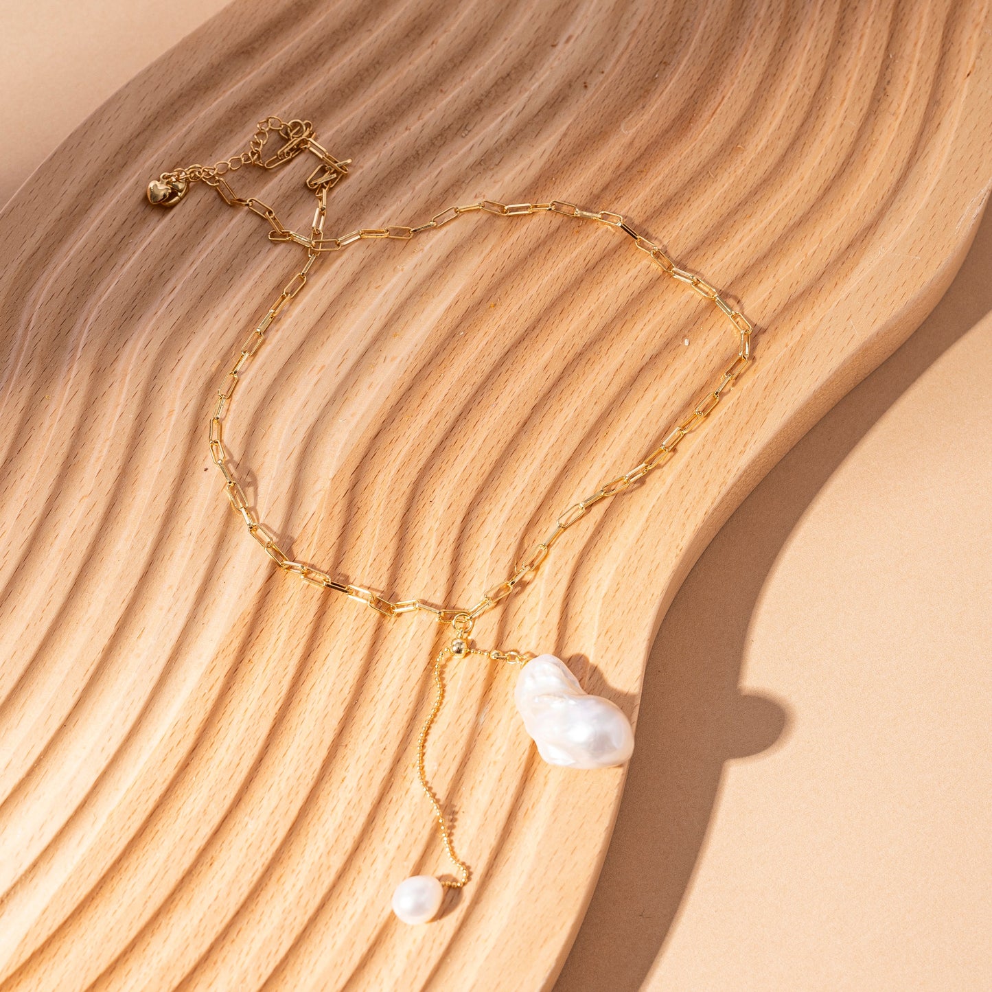 STELLA MARGARITA handcrafted pearl pendant necklace with gold chain on a wooden surface