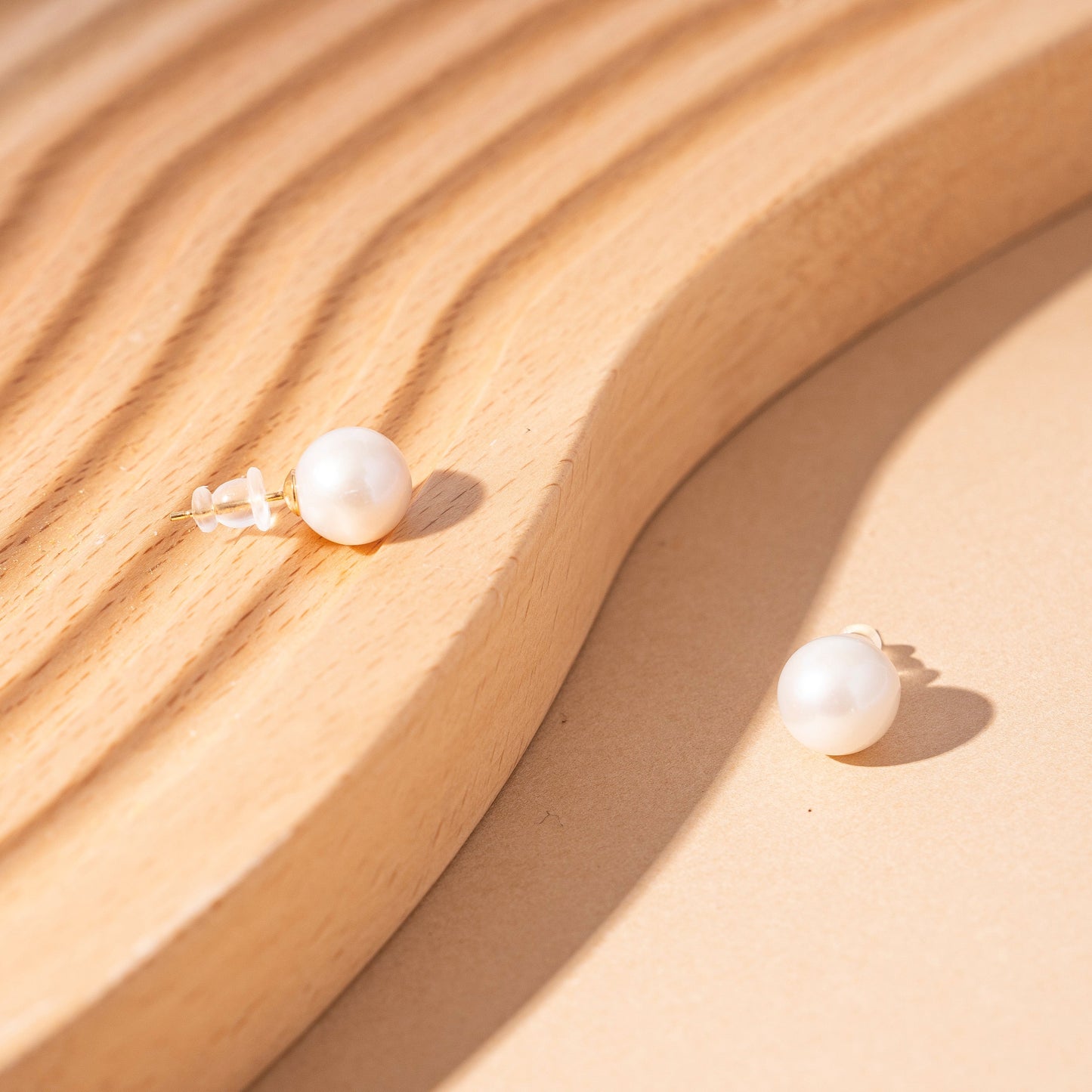 STELLA MARGARITA white pearl earrings for women displayed on a wooden surface with soft lighting