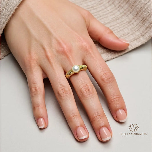 Hand wearing handcrafted gold pearl engagement ring with textured band by STELLA MARGARITA