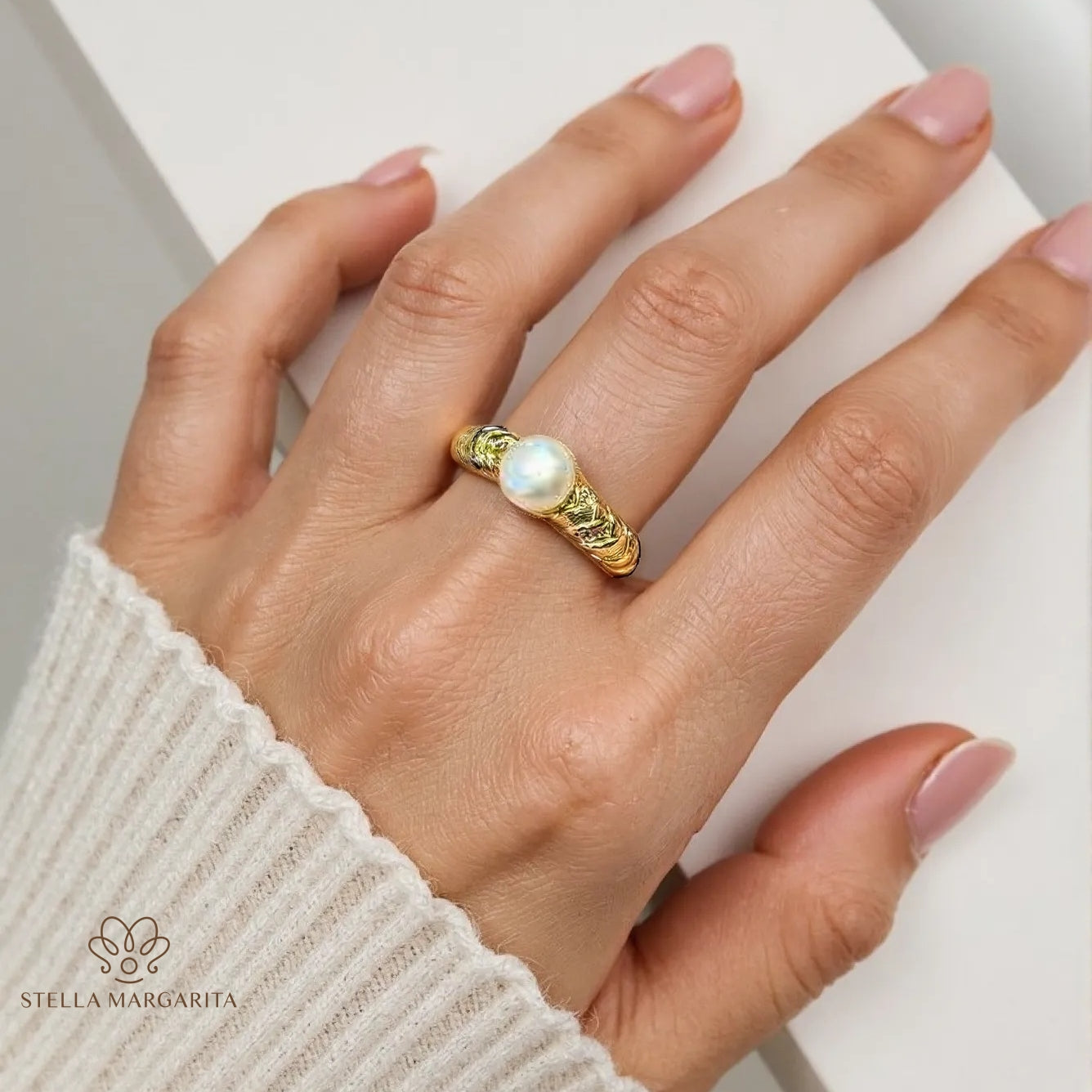 Hand wearing a handcrafted gold pearl engagement ring with intricate detailing by STELLA MARGARITA