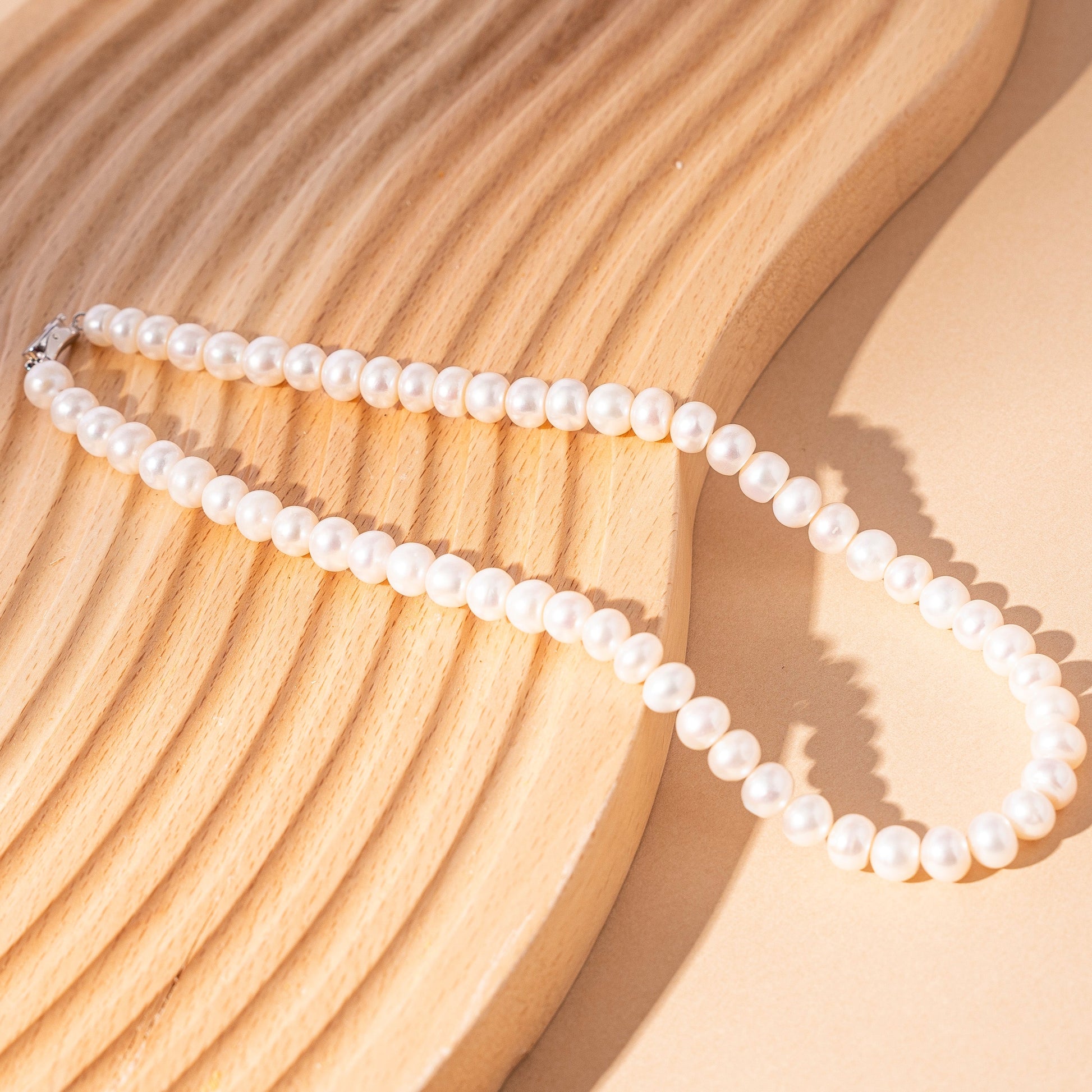STELLA MARGARITA handcrafted pearl necklace for women displayed on a textured wooden surface