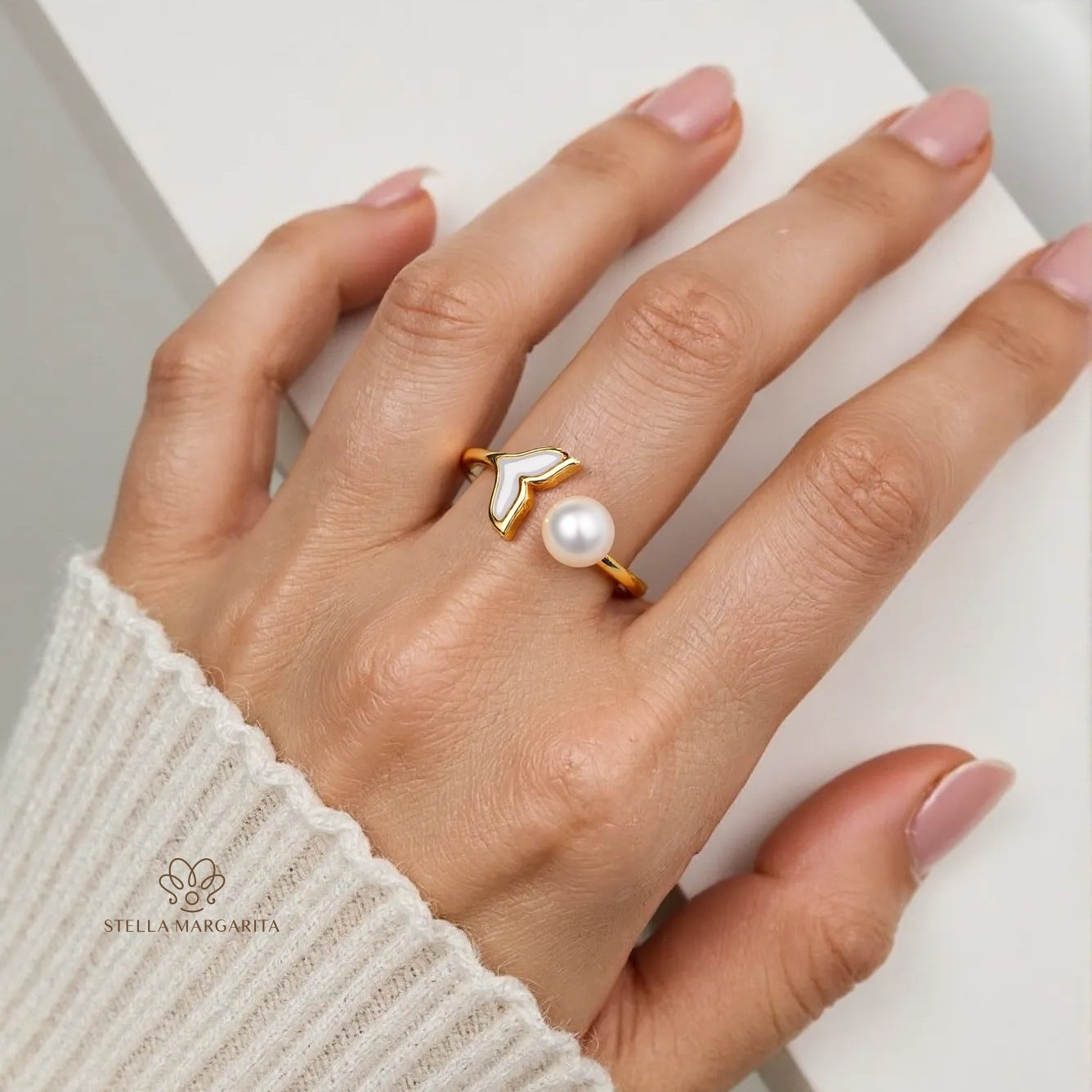 STELLA MARGARITA 18K gold pearl mermaid ring on hand with cream sweater background