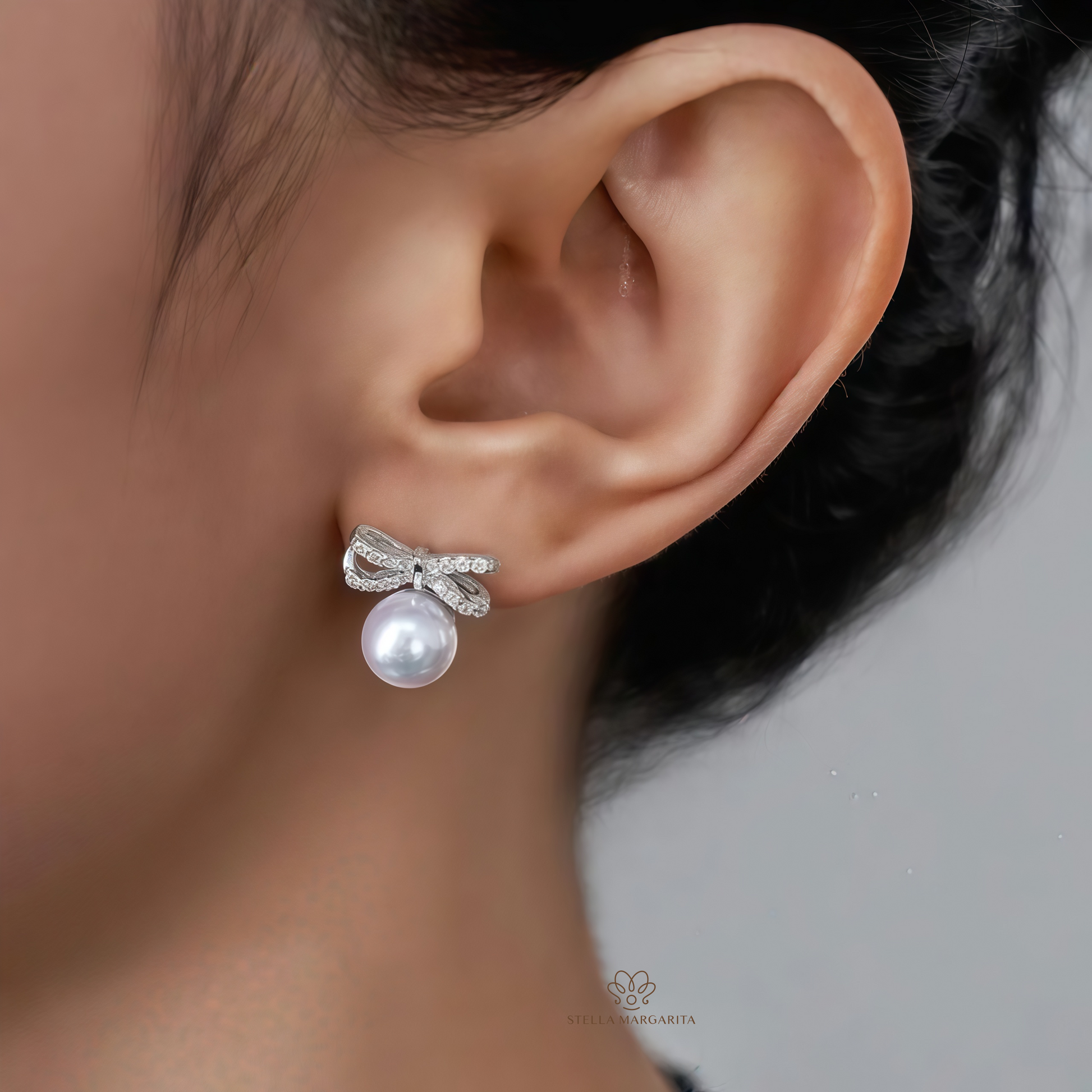 STELLA MARGARITA silver ribbon pearl stud earrings worn on ear with elegant pearl and bow design